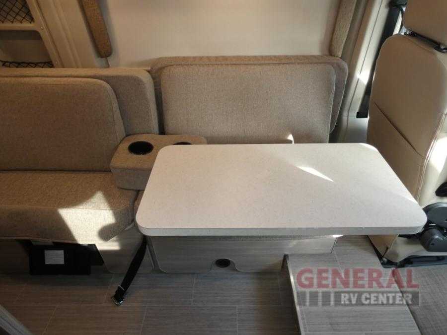 RV rental interior: cozy dinette with light-colored bench seats, a central table, and cup holders. — photo 8