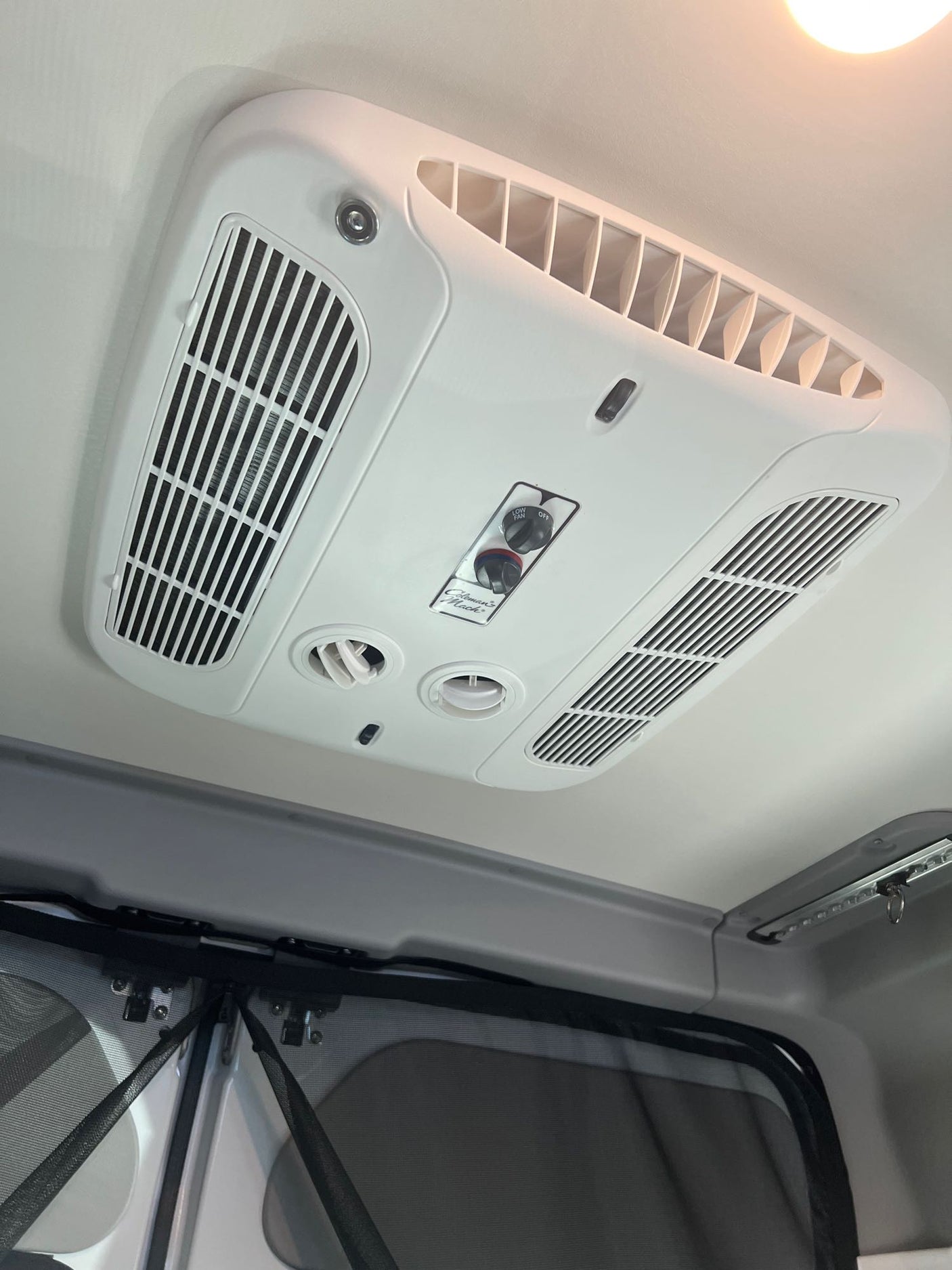RV rental: Ceiling-mounted Coleman Mach air conditioner unit with multiple vents and control knobs for climate comfort.