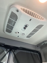 RV rental: Ceiling-mounted Coleman Mach air conditioner unit with multiple vents and control knobs for climate comfort.