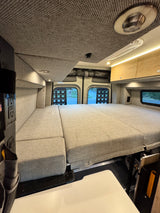 Relaxing RV rental interior with a spacious, modular bed, overhead storage, and ambient lighting.