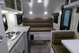 RV rental interior: a bright, modern space featuring a compact kitchen, long bench, and dinette seating area.