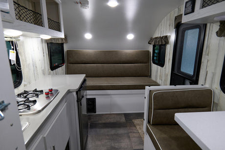 RV rental interior: a bright, modern space featuring a compact kitchen, long bench, and dinette seating area.