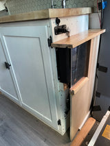 RV rental custom build: kitchenette with white cabinets, wood counter, and a visible ROVER solar charge controller.