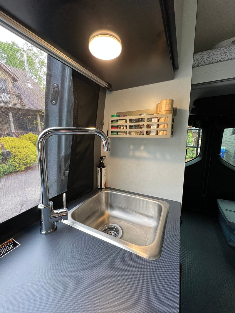This RV rental features a practical kitchenette with a stainless steel sink, chrome faucet, and a wall-mounted spice rack. — photo 17