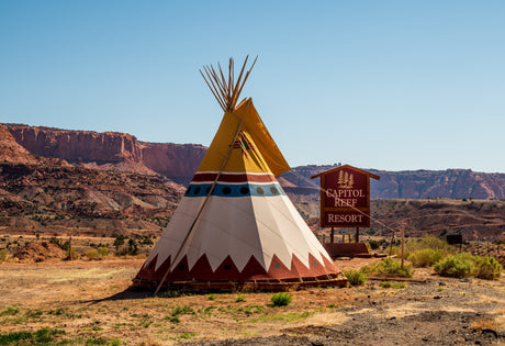 A vibrant teepee at Capitol Reef Resort, nestled in a red rock desert. Look closely for a hidden RV rental, perfect for scenic Utah exploration.