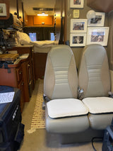 Cozy RV rental interior featuring passenger seats, a kitchenette, and bed. Ideal for mobile living.