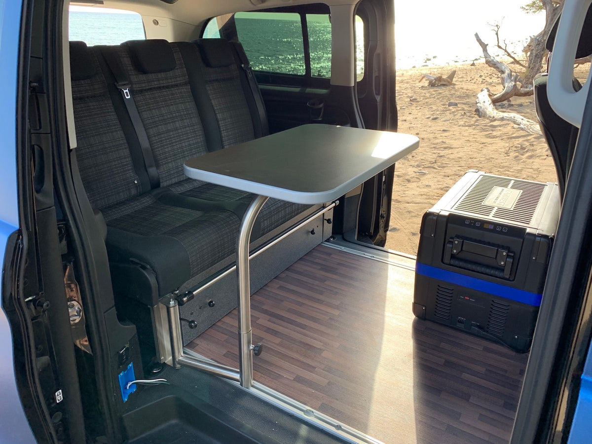 Experience beachside comfort in this rv rental. Interior view shows rear seating, adjustable table, and portable cooler. — photo 9