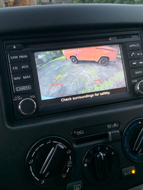 Dashboard screen shows an orange RV rental in rearview camera view, with parking lines and a safety message.