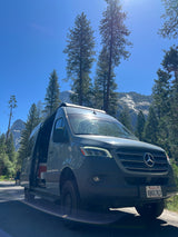 Exploring Yosemite with an RV rental: a grey Mercedes Sprinter van on a sunny day surrounded by trees and mountains.
