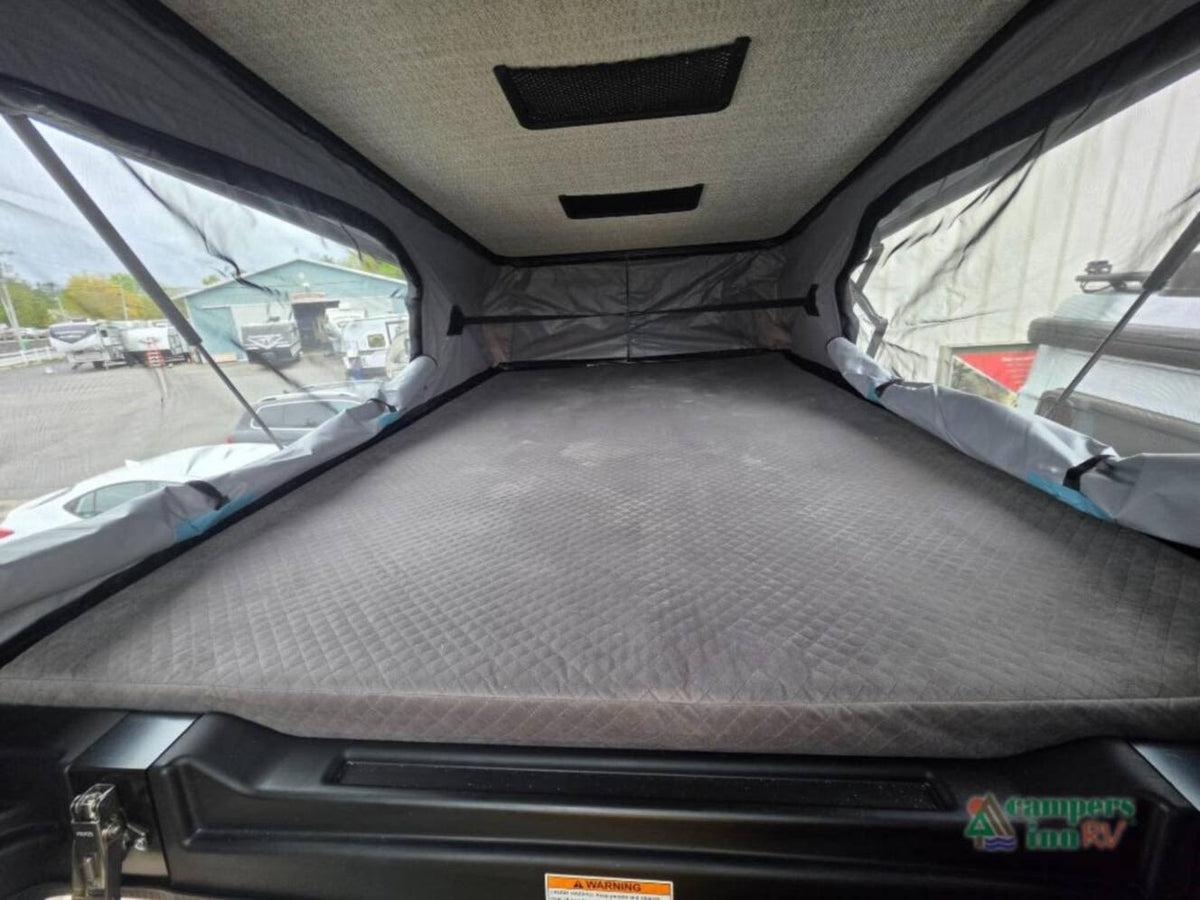  and passenger seats for your next adventure.|Cozy pop-up RV rental bed area with quilted mattress & mesh windows offering an outdoor view. Ideal camper sleeping space.|RV rental: Compact wet bath with an integrated toilet and shower. A mirrored door helps visually expand this small bathroom space. — photo 5