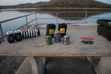 Perfect RV rental setup: lakeside picnic table with camping lanterns, Wise Owl hammocks, tumblers & grill.