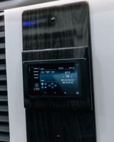 A Garmin RV control panel on a dark wood-grain wall, managing climate, lights, and radio. Perfect for an RV rental.