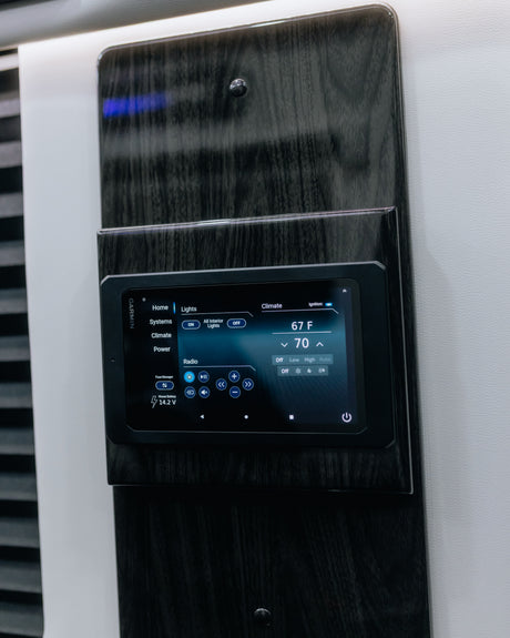 A Garmin RV control panel on a dark wood-grain wall, managing climate, lights, and radio. Perfect for an RV rental.