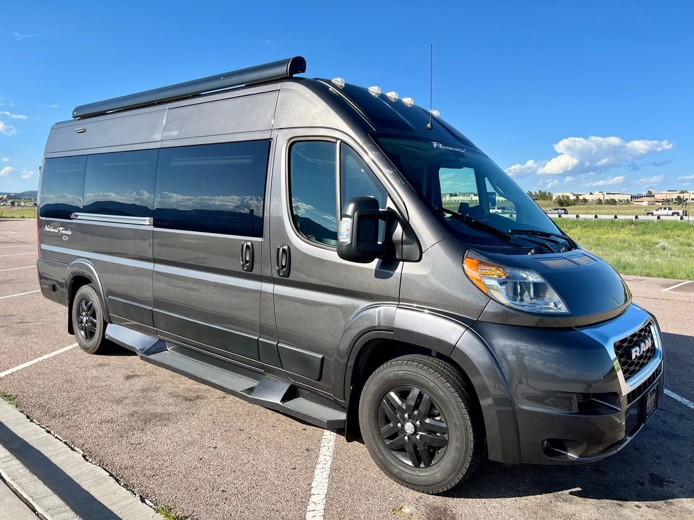 This sleek grey RV rental, a ProMaster camper van, is ready for adventure under a clear sky.