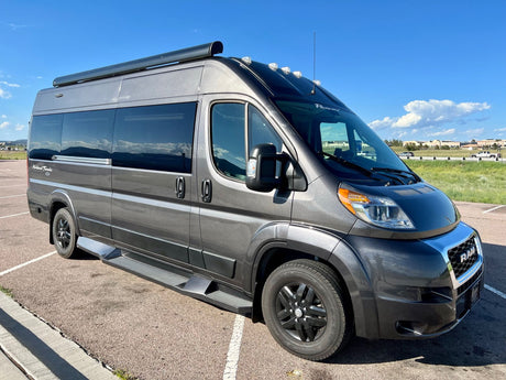 This sleek grey RV rental, a ProMaster camper van, is ready for adventure under a clear sky.