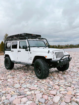 White Jeep Wrangler, iKamper rooftop tent on rocky riverbed. Overlanding ready! Explore unique rv rental options for adventure.
