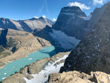 Panoramic view of a vibrant turquoise glacial lake nestled among rugged, snow-dusted mountains. Perfect for an RV rental escape.