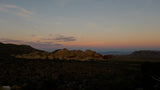 Desert twilight hues over stunning red rock formations and sparse vegetation. Your RV rental adventure awaits in this expansive landscape.