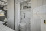 RV rental's modern wet bath: a compact toilet, shower, and sink faucet. Clean grey and white interior design.