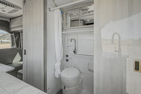 RV rental's modern wet bath: a compact toilet, shower, and sink faucet. Clean grey and white interior design.