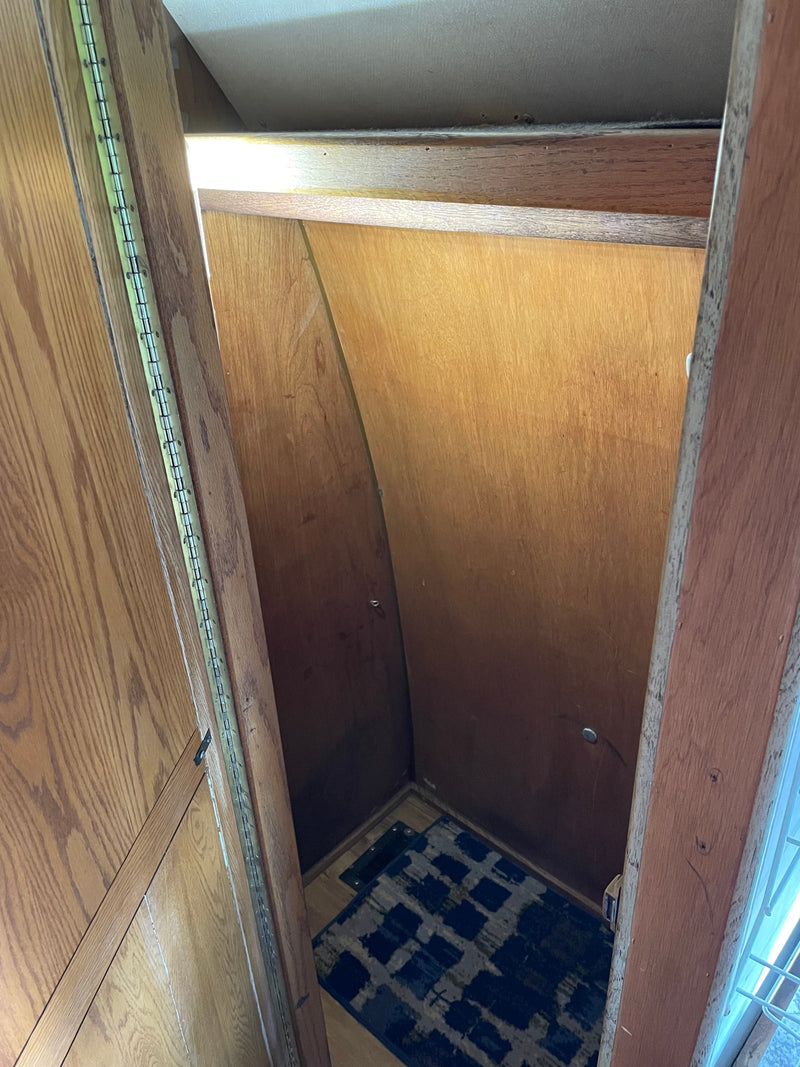 RV rental interior: narrow wood-paneled closet with continuous hinge and floor mat, offering compact storage. — photo 10
