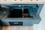 RV rental utility access: open storage with electrical components & a Dometic fridge in a camper van interior.