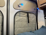 RV rental interior: illuminated blue reading lights, padded window cover, & overhead cabinet detail.