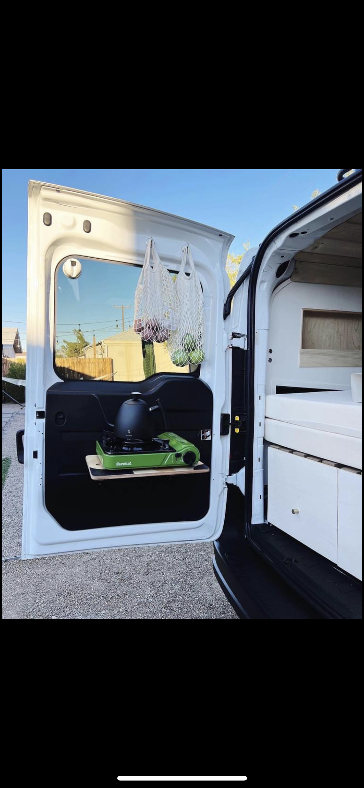 RV rental camper van features: rear door kitchen with stove, kettle, produce bags, & interior storage/bed.
