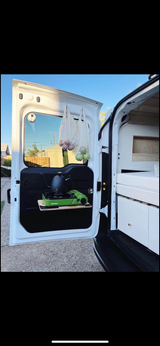 RV rental camper van features: rear door kitchen with stove, kettle, produce bags, & interior storage/bed.