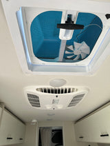 Looking up inside an RV rental: Features a ceiling vent with fan, air conditioning unit, and overhead storage cabinets.