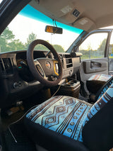 Interior of an rv rental van with steering wheel, dashboard (197k miles), and distinctive blue patterned seat covers.