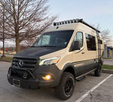 Storyteller Overland Mercedes Sprinter adventure rv rental van, with off-road tires, rooftop lights, and rugged bumper.