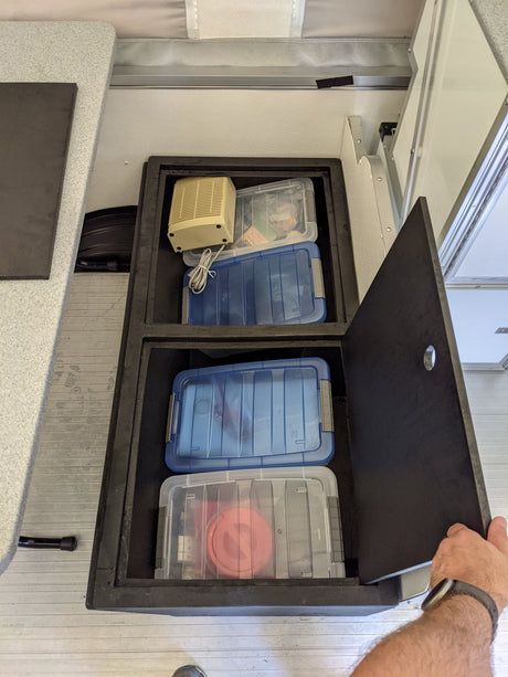 Organized RV rental interior storage: view of built-in bins holding clear containers, including a fan.