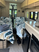 This RV rental features a well-appointed interior with twin beds, a small kitchen, and scenic views outside.