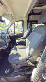 Inside this Ram rv rental van: a view of the front cabin, showing gray fabric seats, steering wheel, and dash.