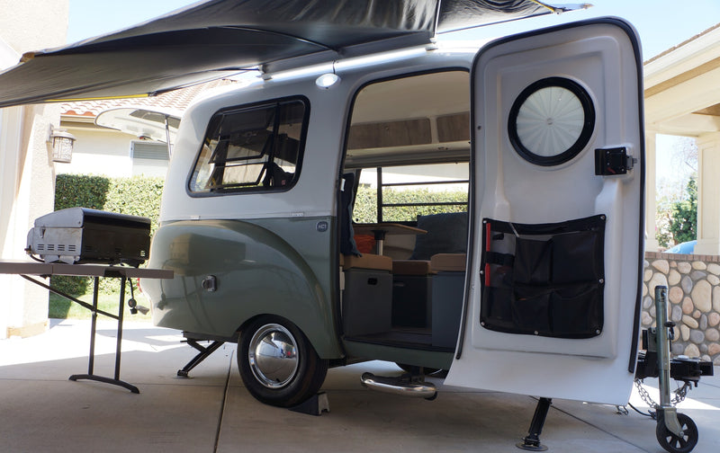 This retro Happier Camper HC1 travel trailer, an ideal RV rental, is set up outdoors with its door open and awning extended. — photo 8