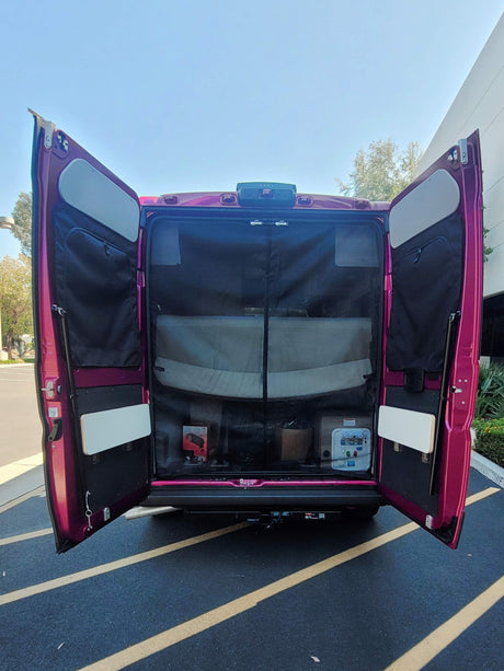 Open rear doors of a purple RV rental show a functional interior with storage pockets, a table, and mesh screen.