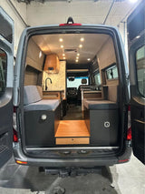 Explore this converted camper van's interior. Designed for RV rental, it features comfy benches, a kitchen, and a clever step with storage.