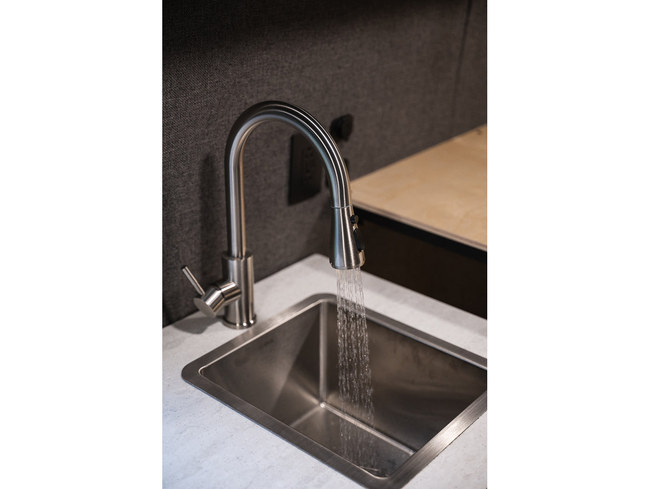 RV rental interior: Modern faucet running water into a stainless steel sink. Compact kitchen space.