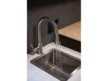 RV rental interior: Modern faucet running water into a stainless steel sink. Compact kitchen space.