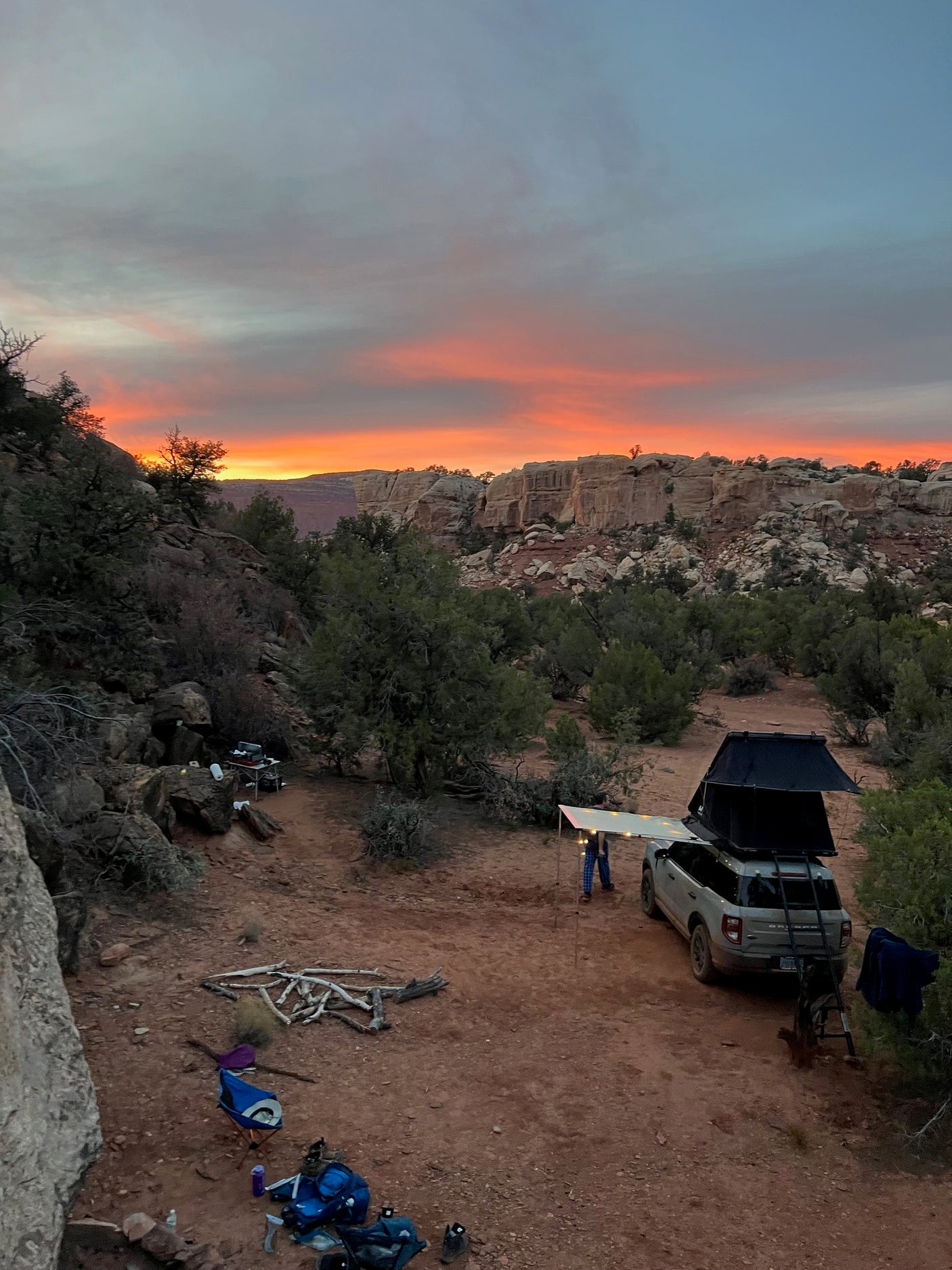 Vibrant desert sunset at a unique RV rental camping spot. SUV with rooftop tent, perfect for outdoor adventures.