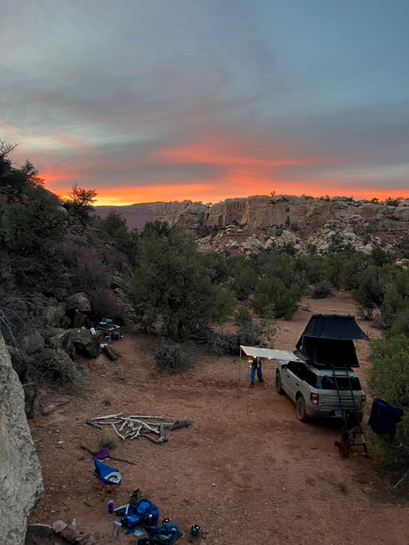 Vibrant desert sunset at a unique RV rental camping spot. SUV with rooftop tent, perfect for outdoor adventures.