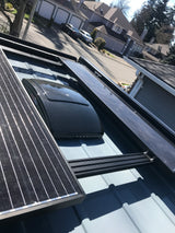 RV rental roof, featuring solar panels and a MaxxAir vent, parked on a residential street with houses in the background.