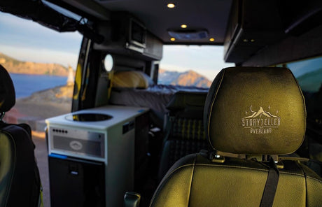 Inside a Storyteller Overland RV rental: equipped kitchen, cozy bed, and panoramic views of ocean and mountains.