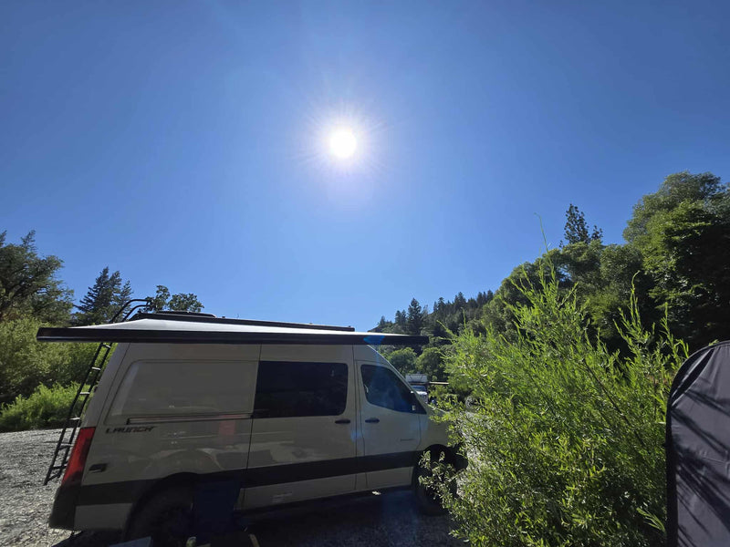  sun glinting on water & trees. Perfect for your next outdoor adventure!|Inside a cozy RV rental: A child sits on the bed looking out the window at trees. Comfort for family travel.|Bright day with an RV rental camper van parked in a sunny natural setting — photo 4