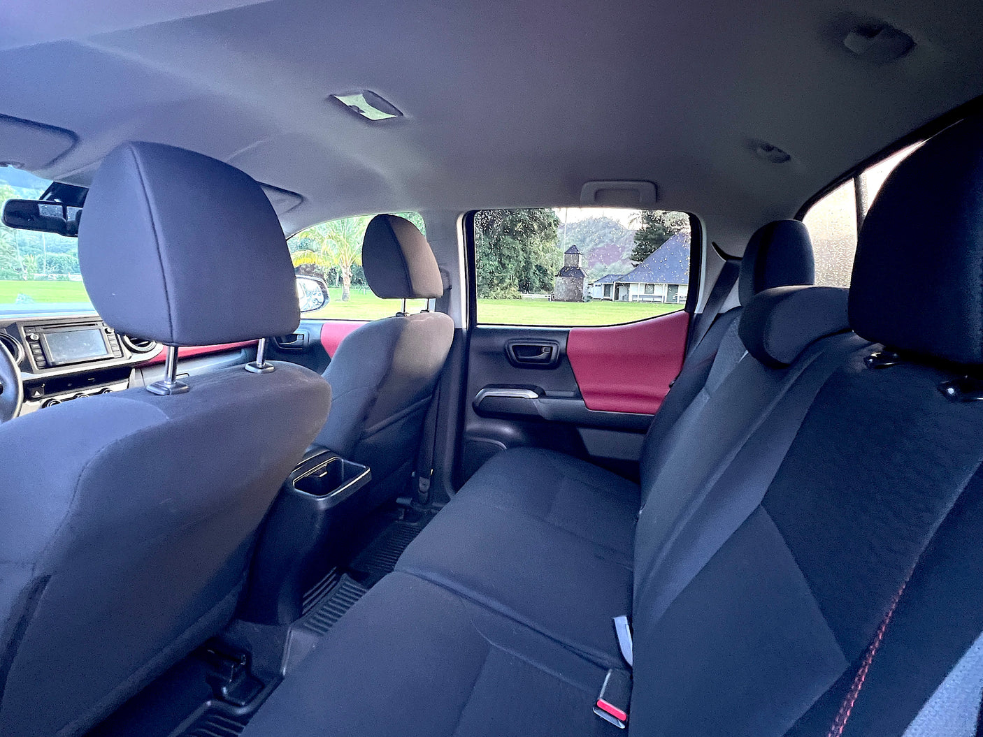 Spacious **vehicle interior** for **RV rental** trips, showing dark seats, red door panels, and outdoor scenery.