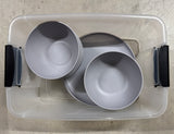 Essential for your RV rental: stackable gray plastic plates and bowls in a clear storage bin.