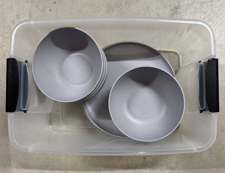 Essential for your RV rental: stackable gray plastic plates and bowls in a clear storage bin.