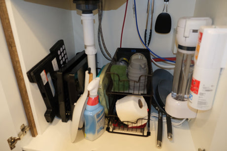 Efficient under-sink storage in an RV rental kitchen, featuring cleaning supplies, small appliances, and plumbing.