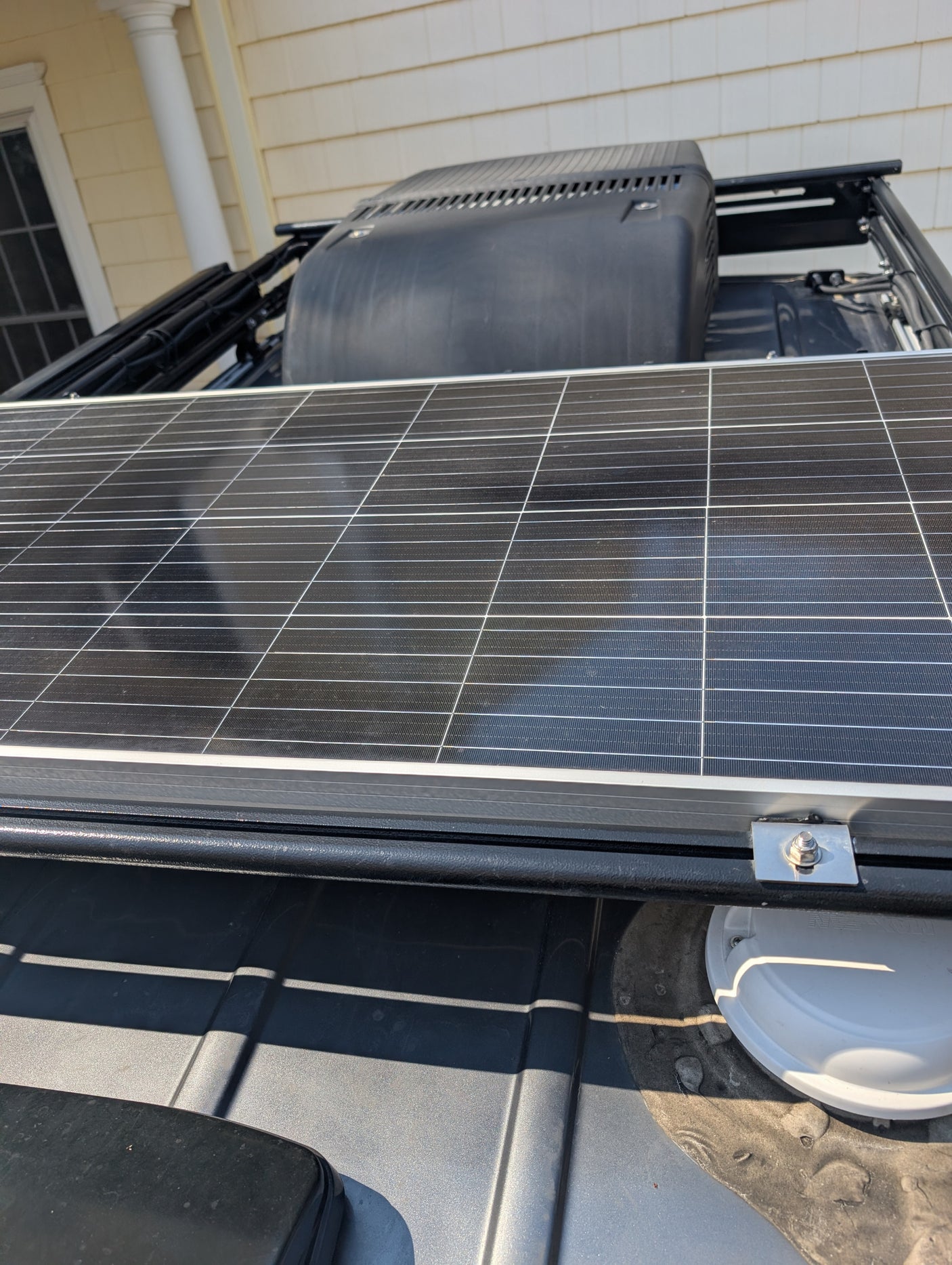 Close-up of a solar panel mounted on an RV roof rack, next to a roof AC unit and Maxx Air vent, ideal for an rv rental.